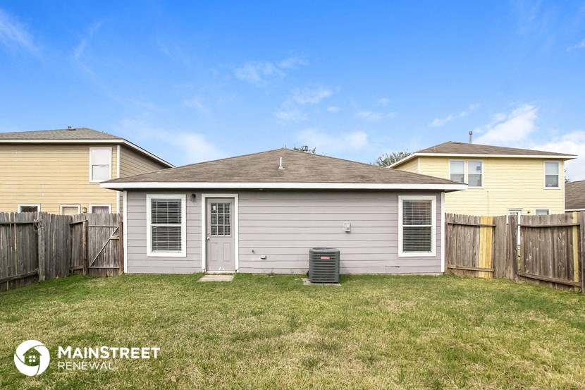 the backyard of a house with a yard and a trash can