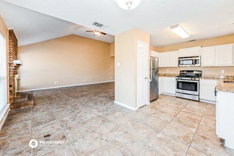 a large kitchen with white cabinets and appliances and tile flooring