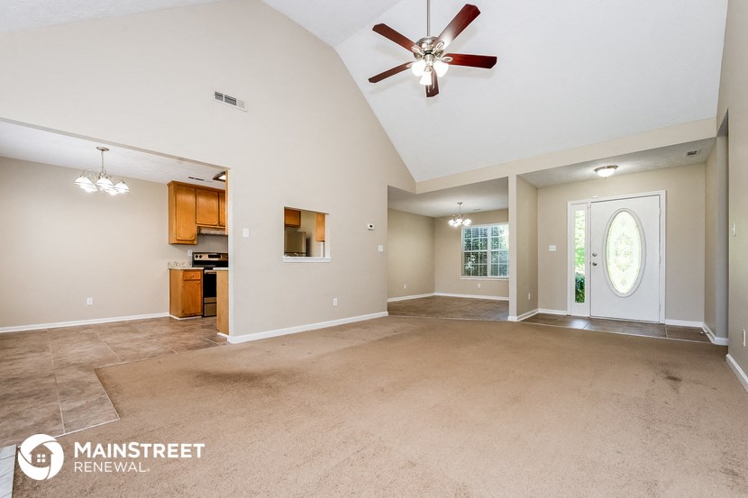 an empty living room with a ceiling fan