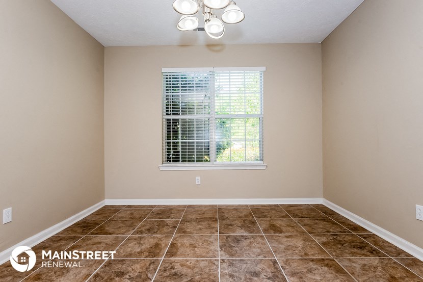 the living room of a home with tile flooring and a window