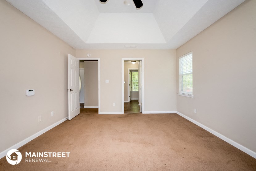 the spacious living room with carpeting and white walls