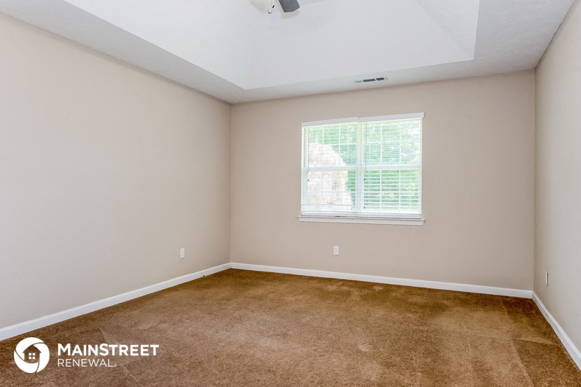 the bedroom of a rental home with carpet and a window
