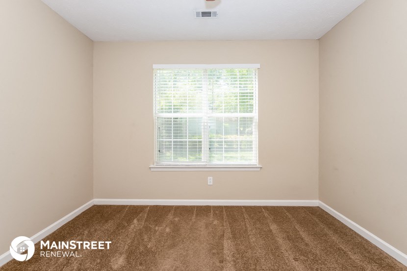 the spacious room has carpet and a large window