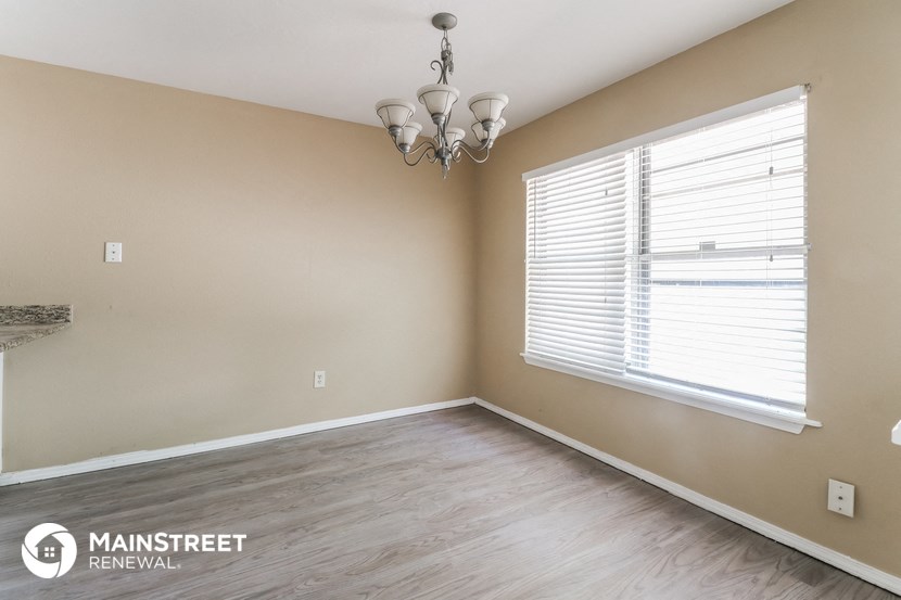 a bedroom with a large window and wood flooring and a chandelier