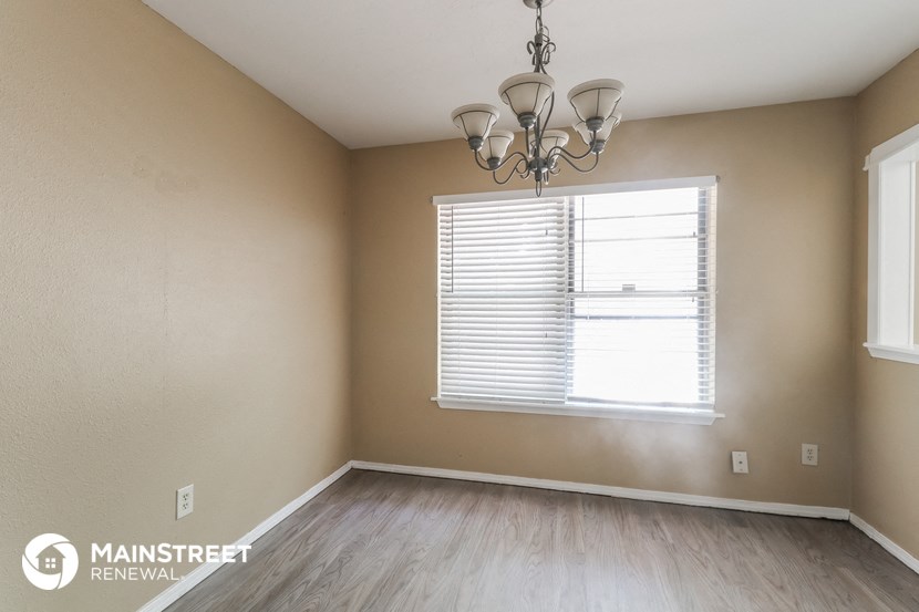 the living room of a home with a large window and wood floors