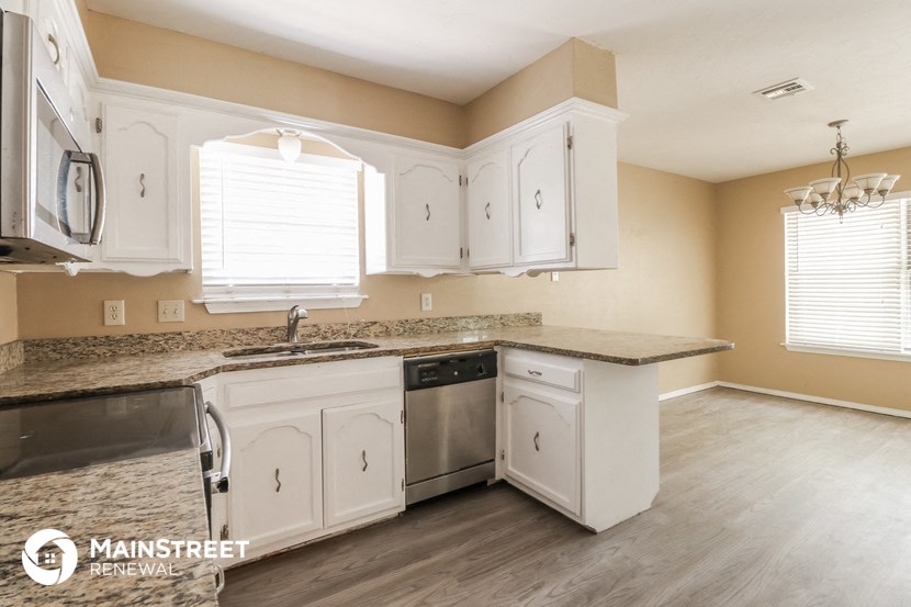 the kitchen after remodeling with white cabinets and granite counter tops
