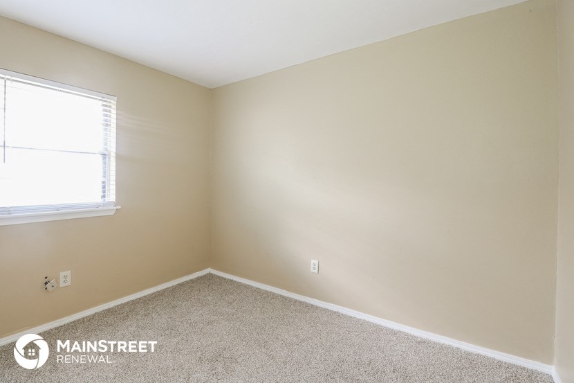 a bedroom with a window and a carpeted floor