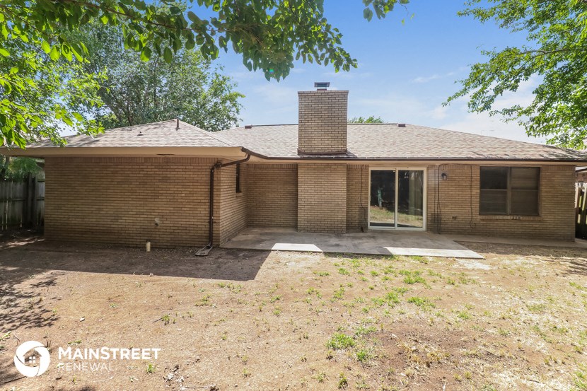 front view of a brick house with a yard and trees