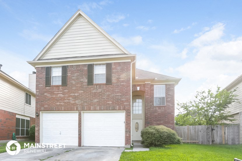 a brick house with two garage doors and a lawn
