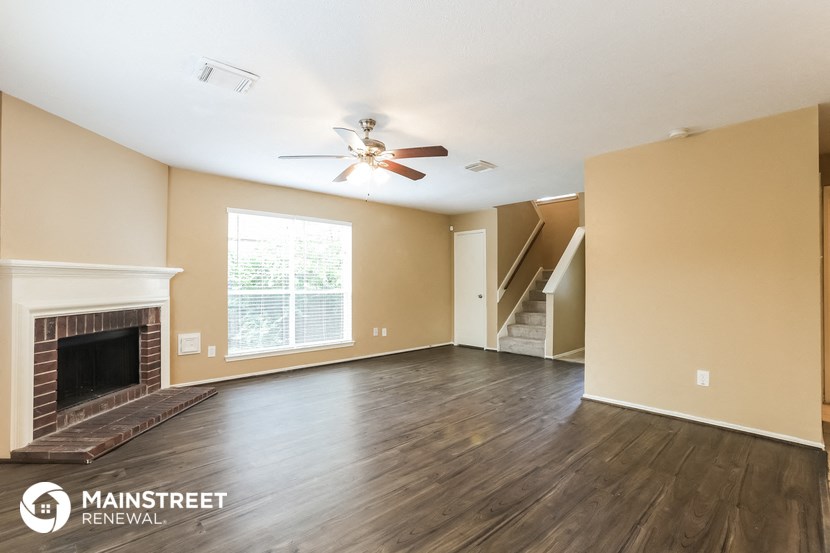 a living room with a fireplace and a ceiling fan