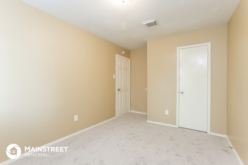 a bedroom with a white door and beige walls and a carpeted floor