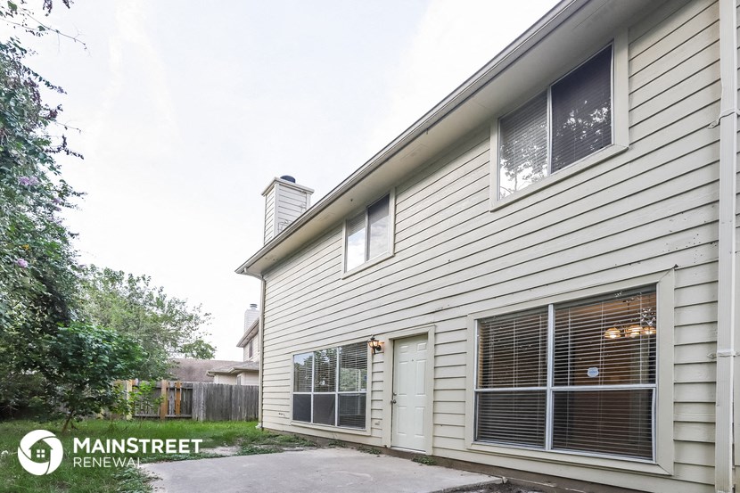 the side of a white house with a garage door and windows