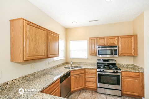 a kitchen with wooden cabinets and granite counter tops and a stove and microwave
