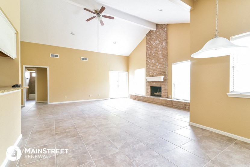 an empty living room with a fireplace and a ceiling fan