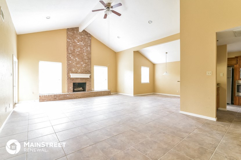 an empty living room with a fireplace and tile flooring