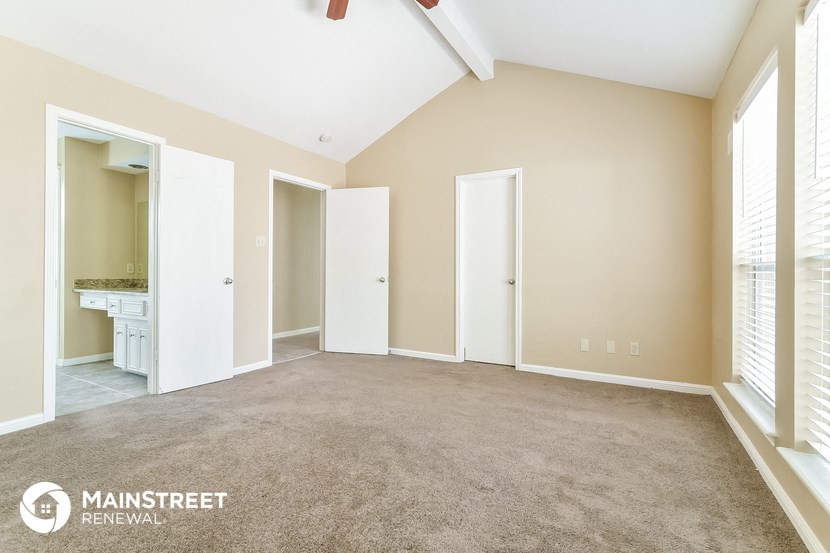 a spacious living room with a carpeted floor and a bathroom