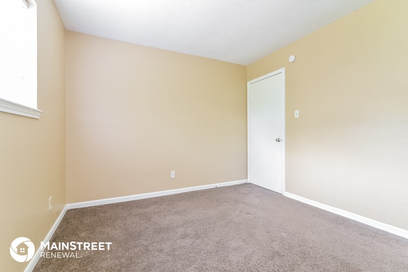 the spacious living room with carpeting and a door to the bedroom
