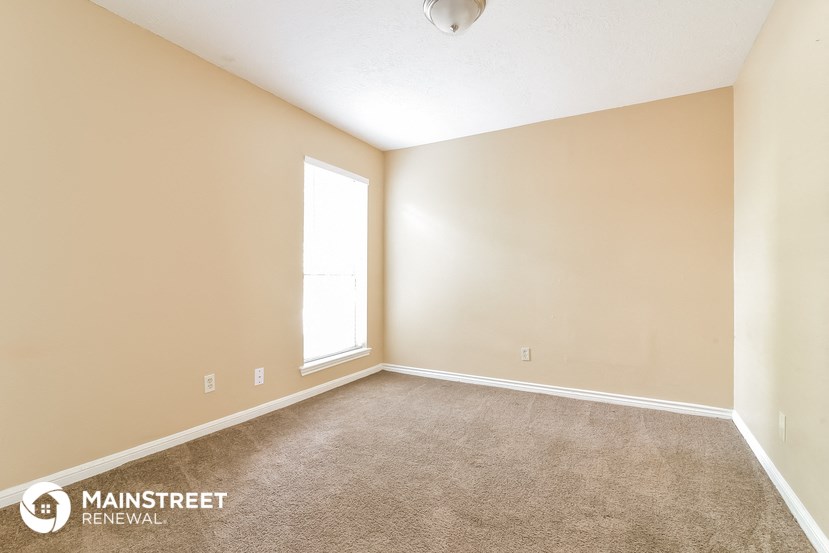 the spacious living room with carpeting and a window