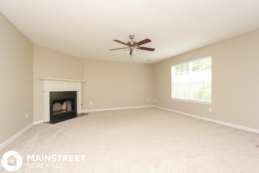 an empty living room with a fireplace and a ceiling fan