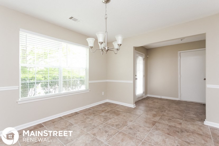 a dining room with a large window and a chandelier