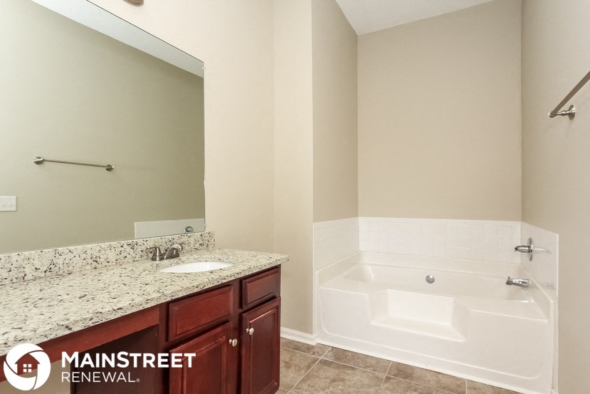 a bathroom with a tub and a sink and a mirror