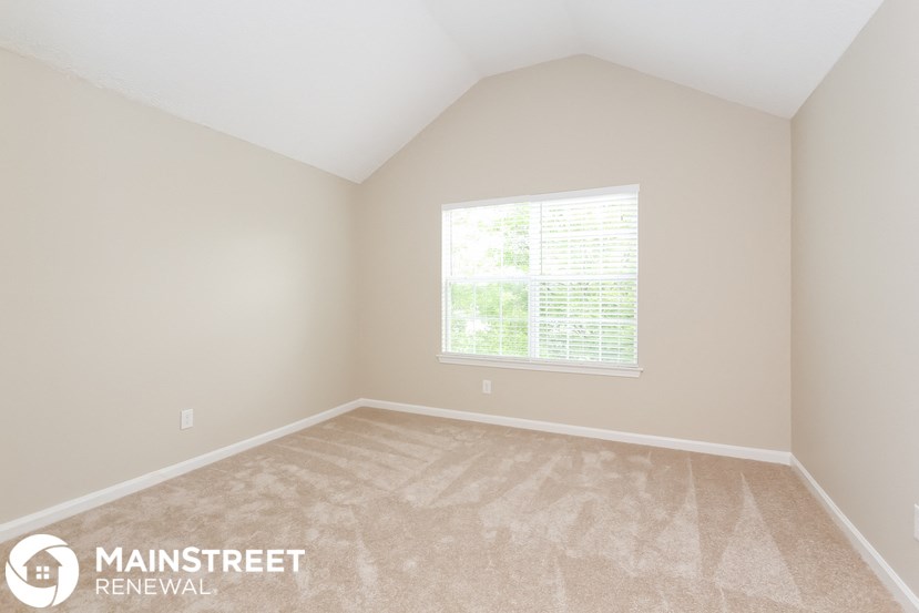 the upstairs bedroom with carpeted floors and a large window