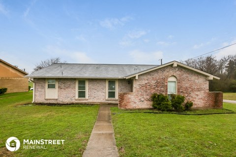 a brick house with green grass and a sidewalk