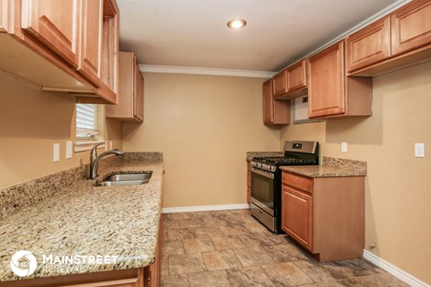a kitchen with wood cabinets and granite counter tops and a stove and sink
