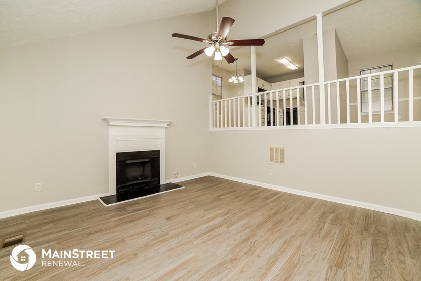 a living room with a fireplace and a ceiling fan
