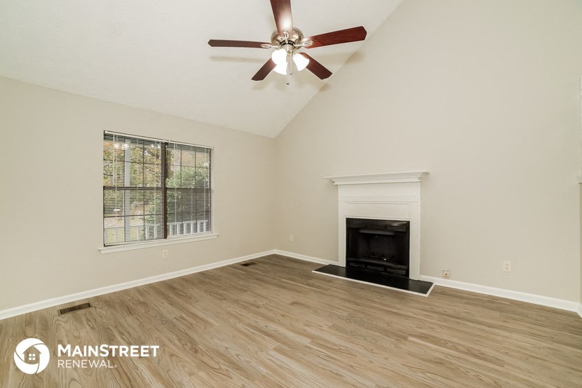 a living room with a fireplace and a ceiling fan