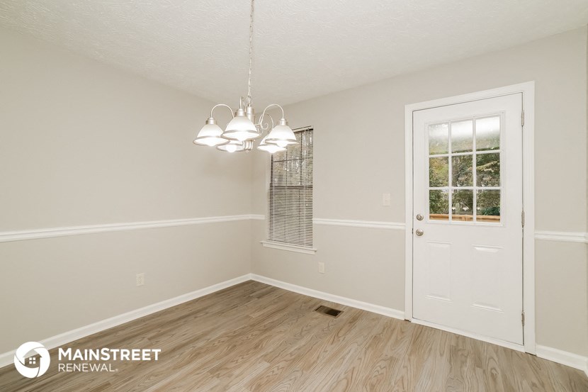 the living room of a house with a white door and wood floors