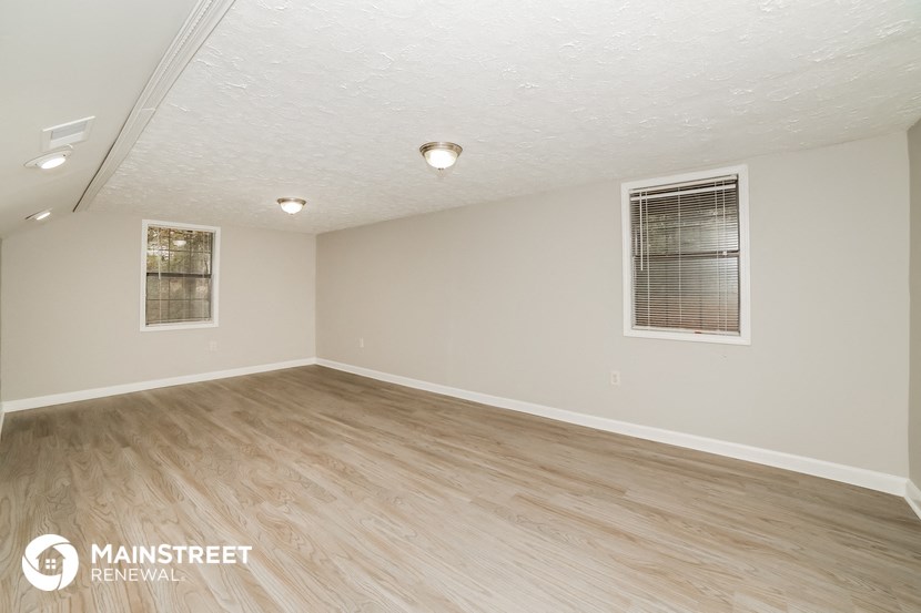 the living room of an apartment with wood floors and white walls