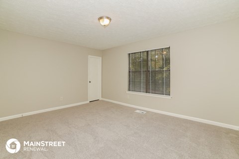 the spacious living room of a manufactured home with carpet and a window