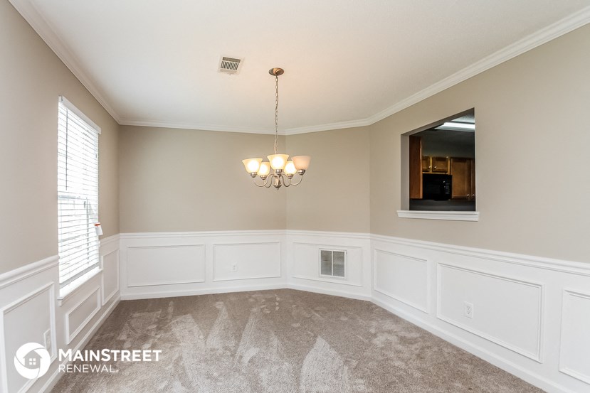 a dining room with white walls and a chandelier
