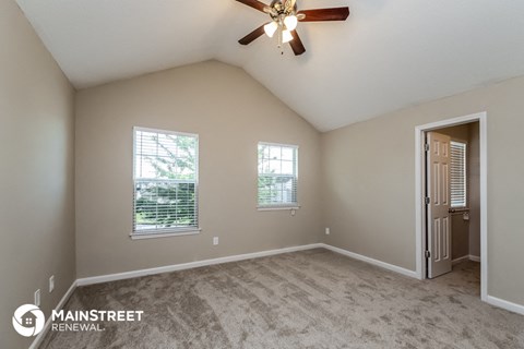the spacious living room with carpet and a ceiling fan