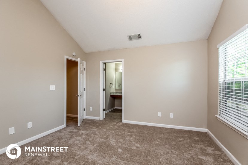 the spacious living room with carpeted flooring and a large window