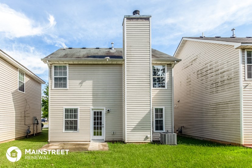 a white house with a tall tower in the middle of two other houses