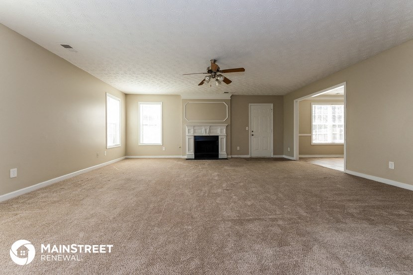 an empty living room with a ceiling fan and a fireplace