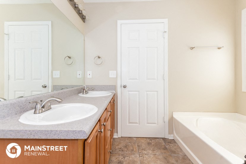 a bathroom with two sinks and a tub and a white door