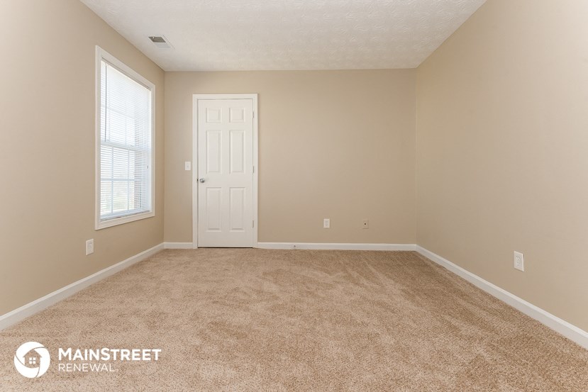 a bedroom with a carpeted floor and a white door