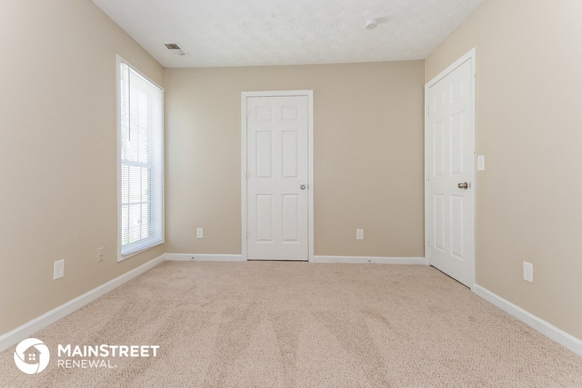 a bedroom with a carpeted floor and two doors