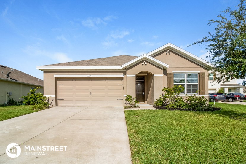 a tan house with a driveway and a garage door