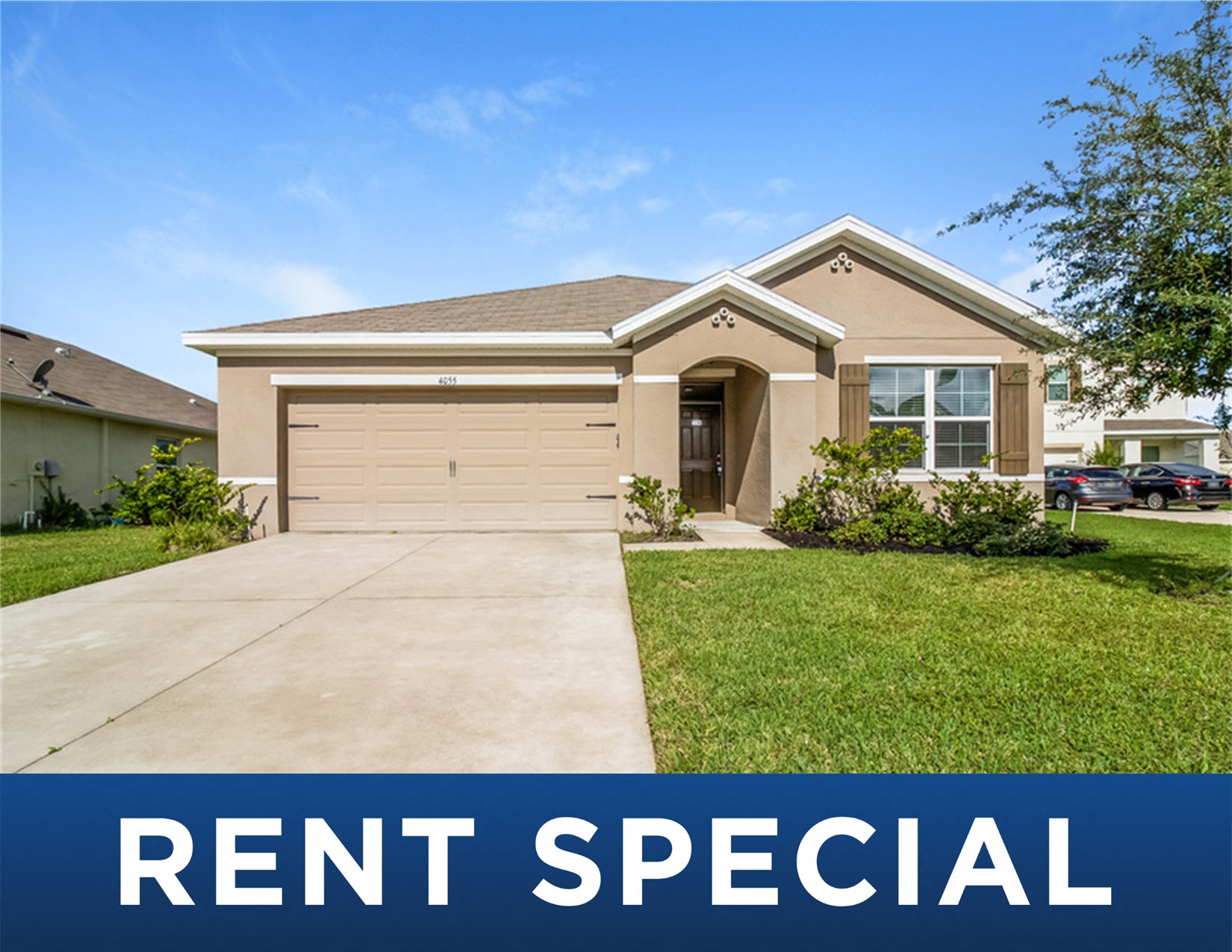 a tan house with a driveway and a rent special sign