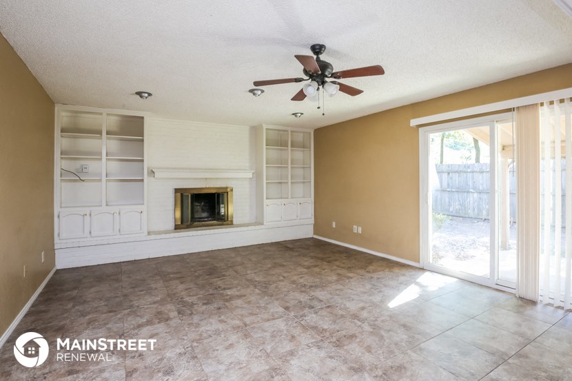 an empty living room with a fireplace and a ceiling fan