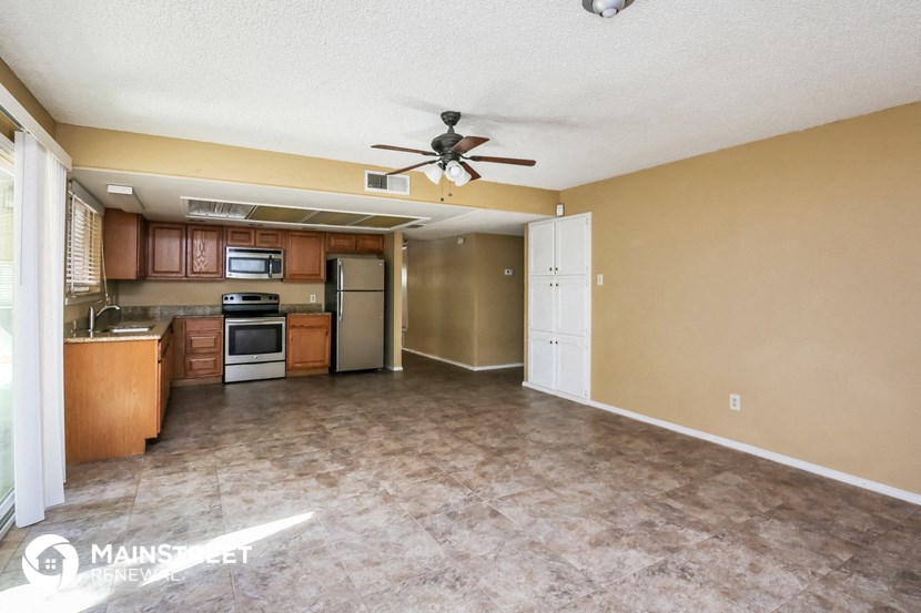 an empty living room and kitchen with a ceiling fan
