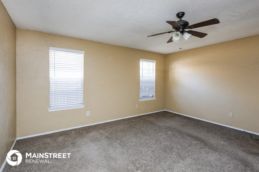 the living room of an empty home with a ceiling fan