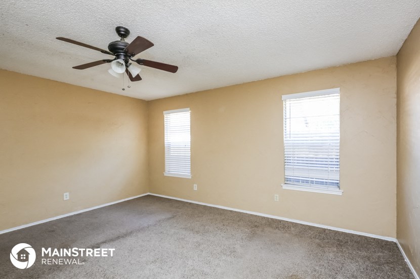 the spacious living room of this manufactured home has a ceiling fan and two windows