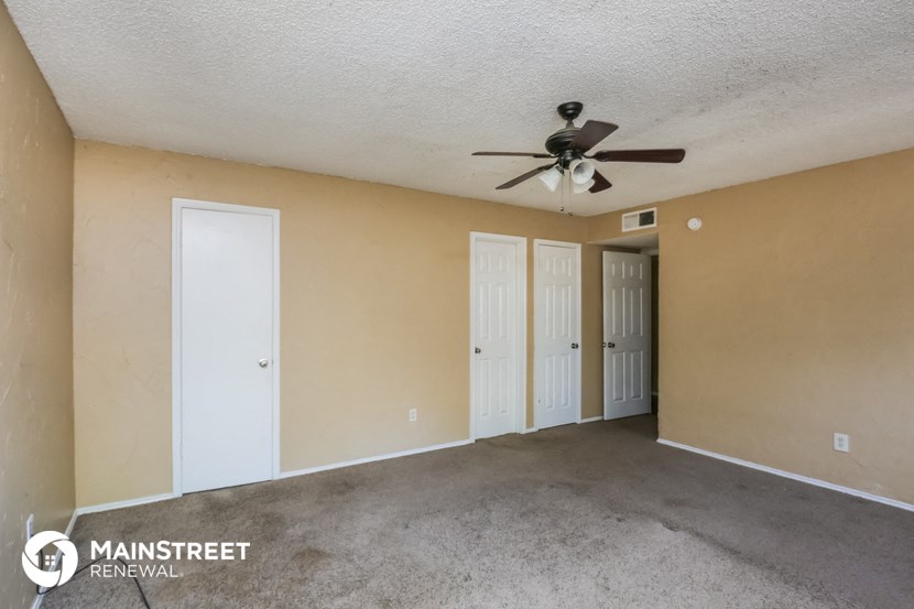 the living room of an apartment with a ceiling fan