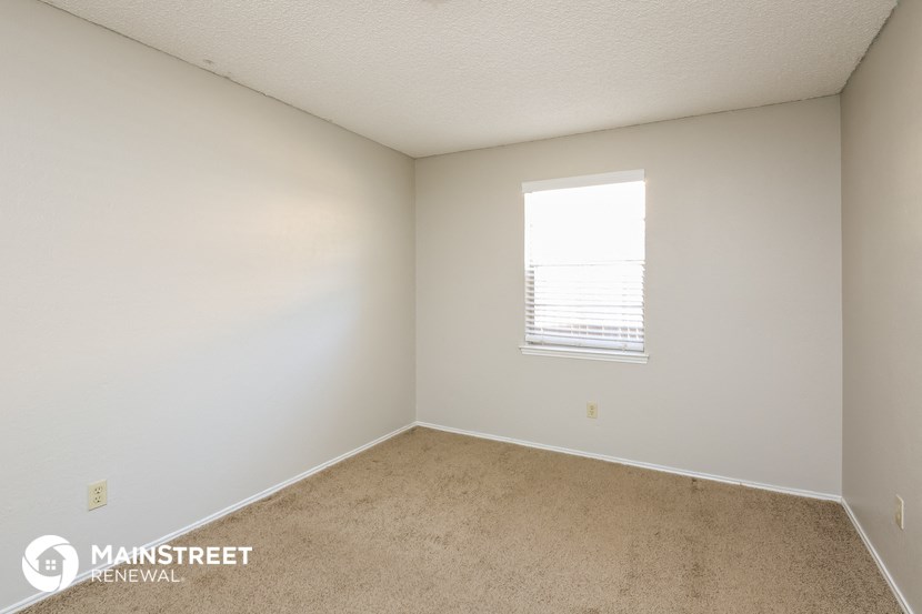 a bedroom with white walls and carpet and a window