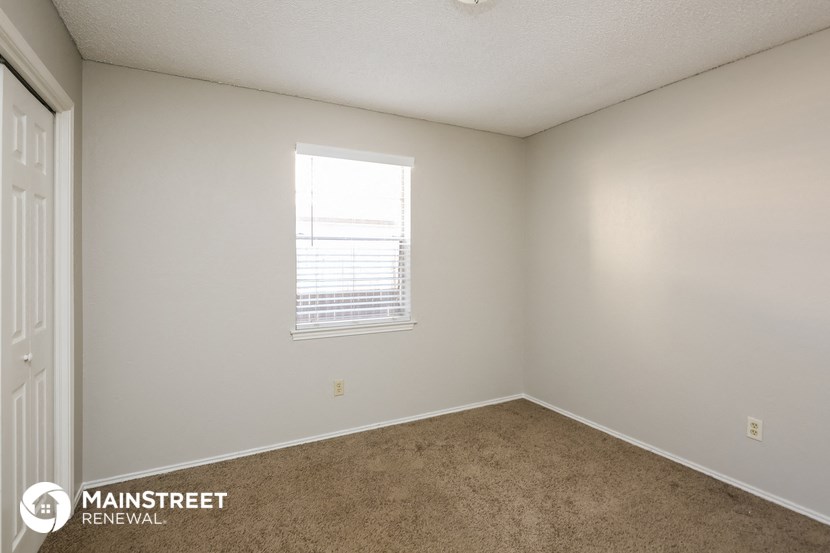 the living room of an apartment with carpet and a window